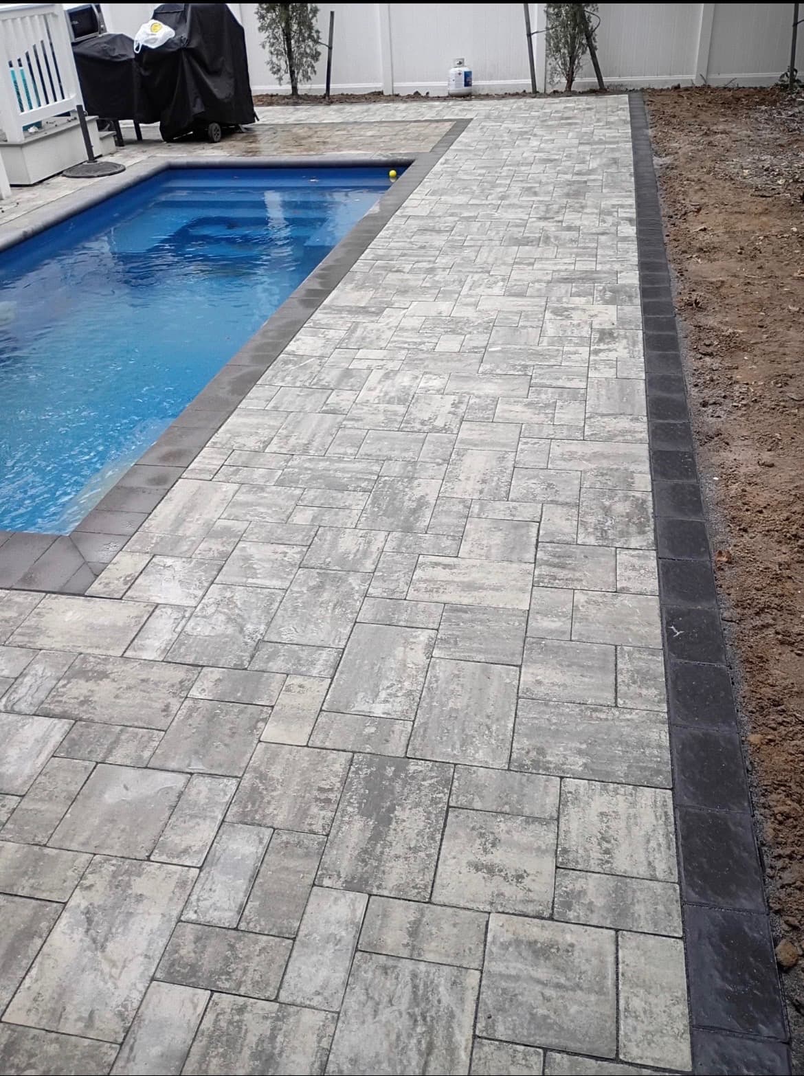 Paver pool deck surrounding a backyard pool